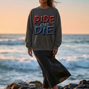 Woman in sweatshirt standing on rocky shore.